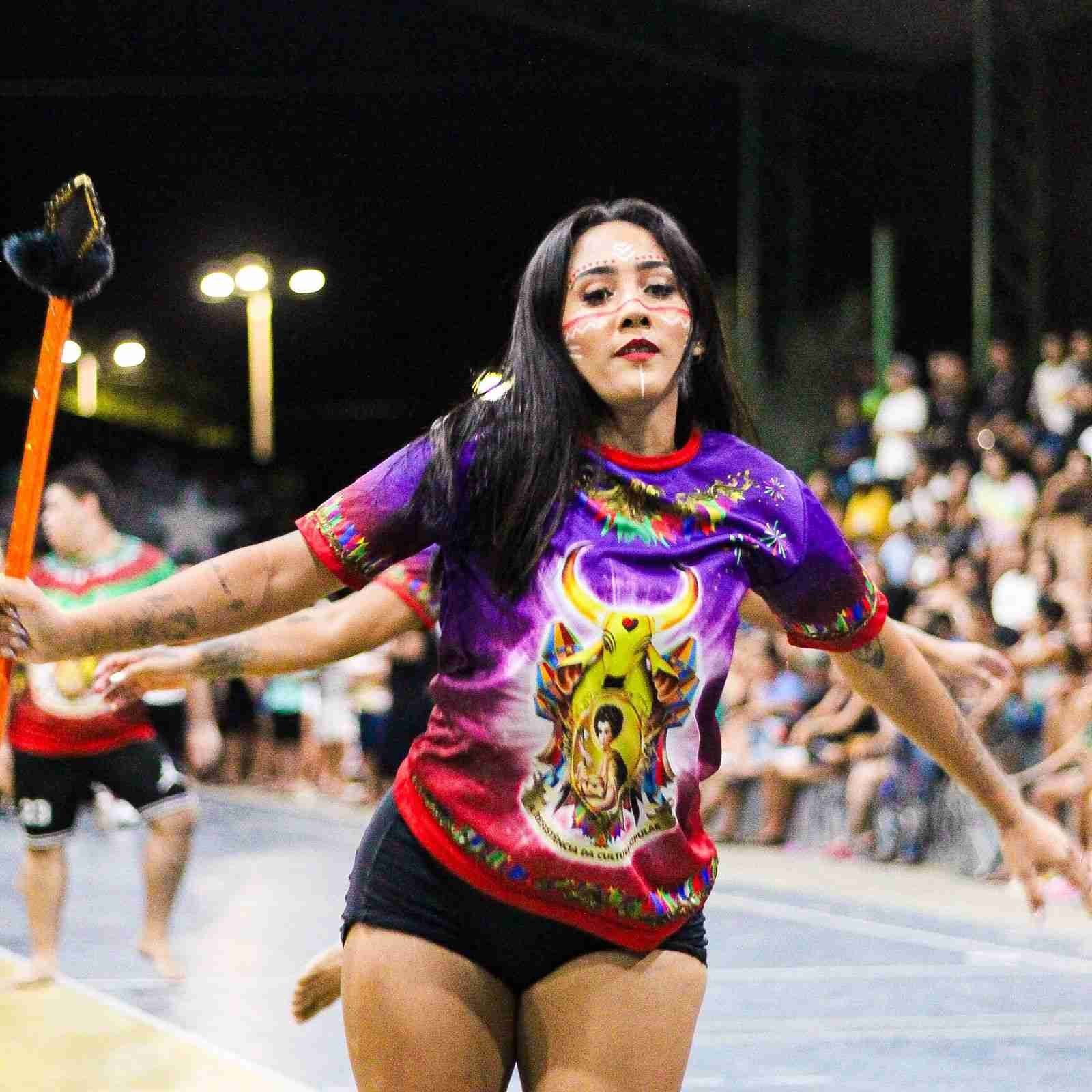 DanÃ§arina performando com bastÃ£o e traje tÃ­pico roxo